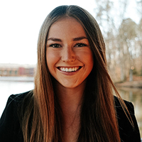 Headshot of a smiling woman with long, brown hair, dressed in business attire.