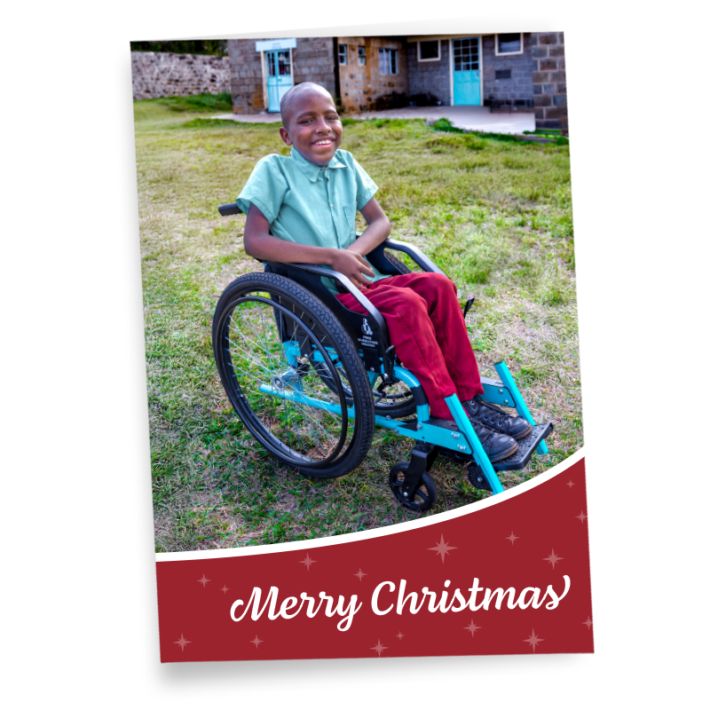 A greeting card saying Merry Christmas, featuring a Kenyan boy in a wheelchair, smiling.