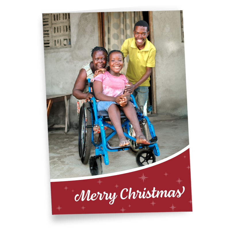 A greeting card saying Merry Christmas, featuring a photo of a Haitian girl in a wheelchair, flanked by her mother and brother.