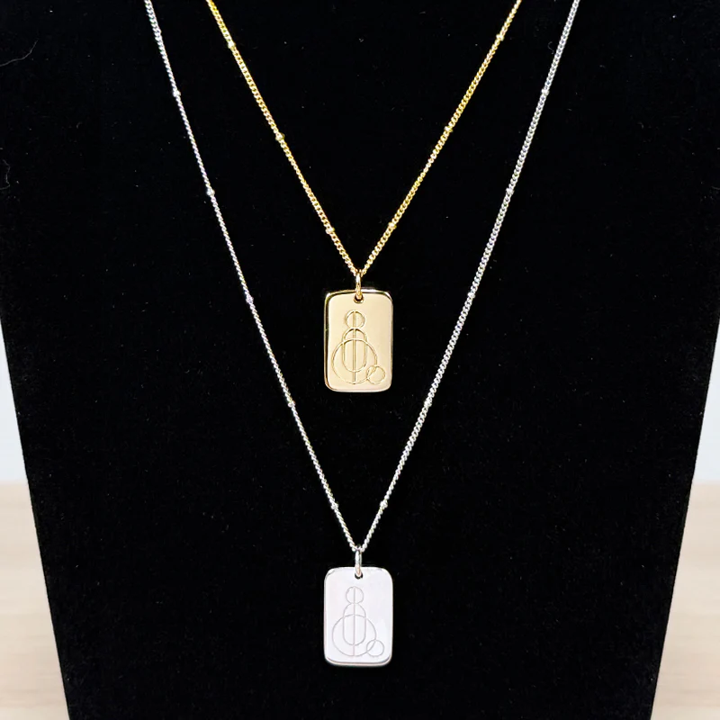 Hope necklaces featuring the Free Wheelchair Mission logo, in gold and silver, on a display.