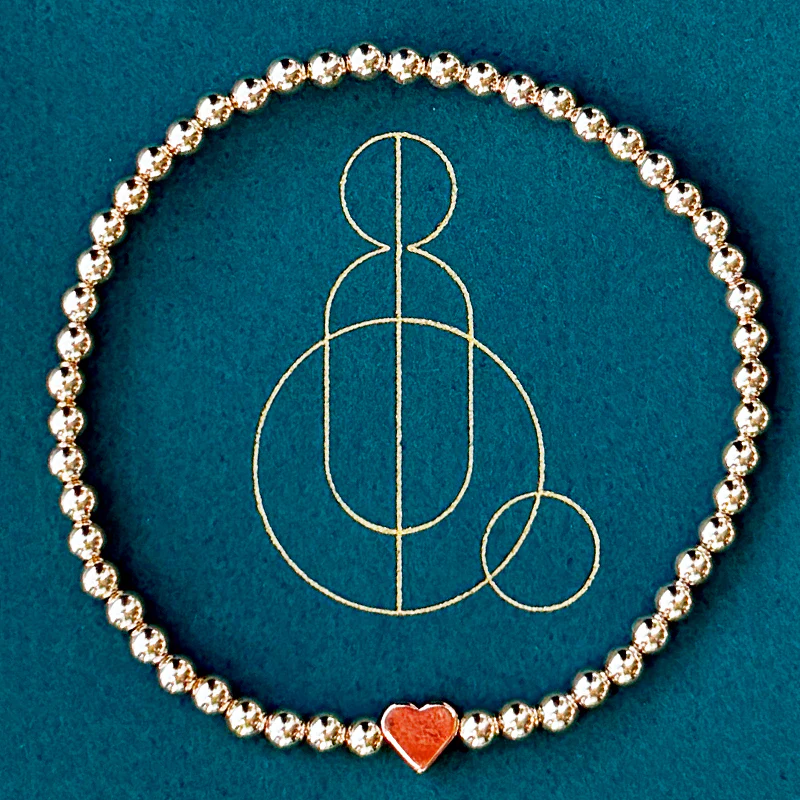 Love bracelet, made of gold beads with a red heart charm on it.