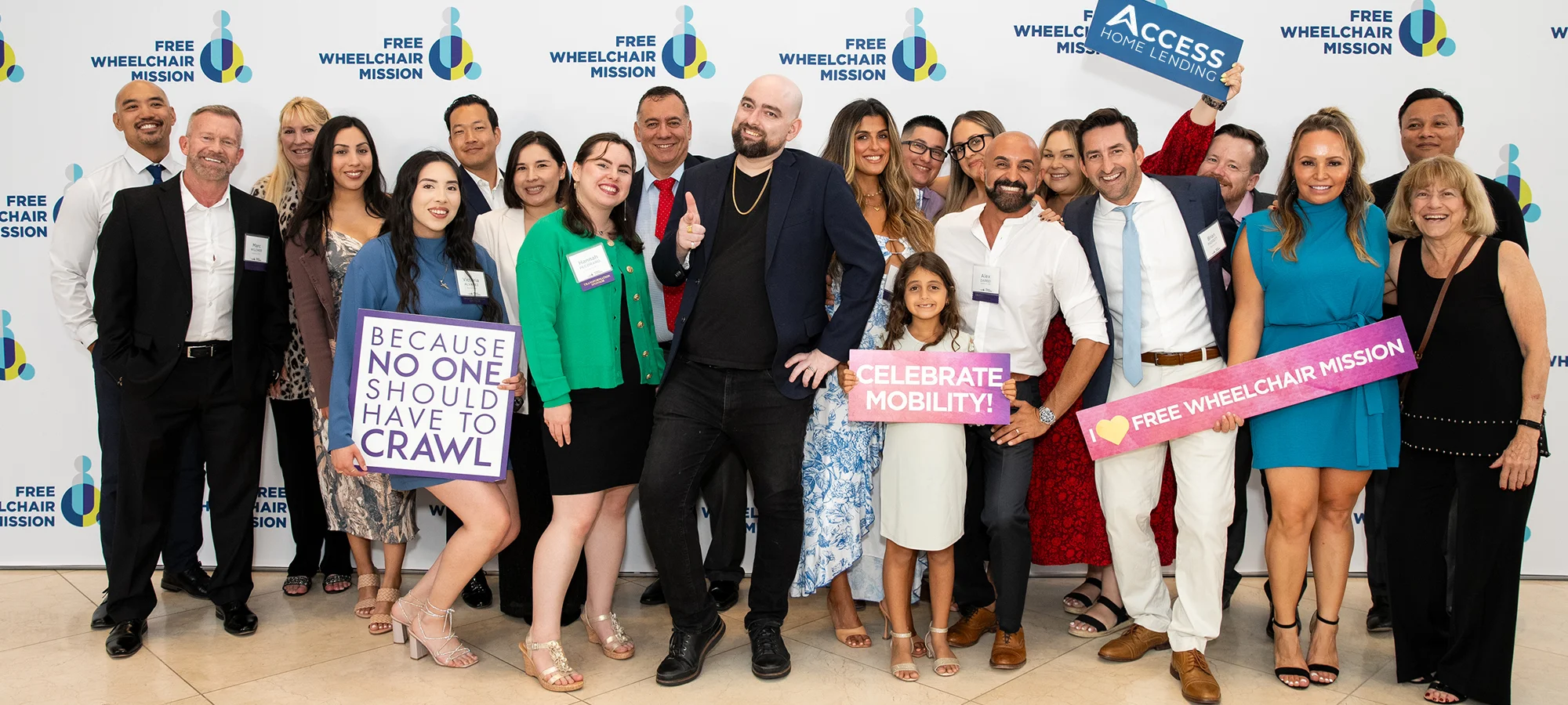 A group of 20 men and women, dressed up for a gala, standing in front of a step and repeat banner, representing their company, Access Home Lending.